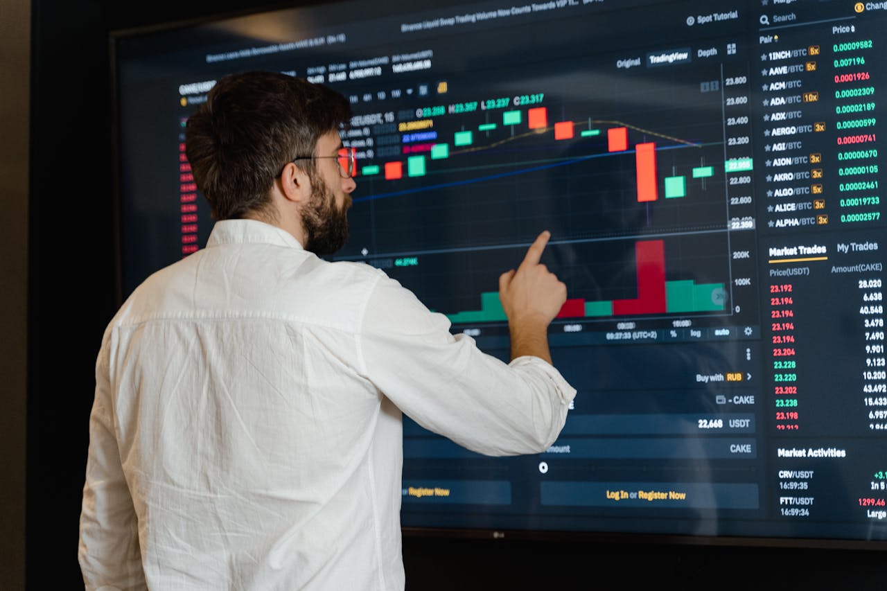 about-02 A man analyzes cryptocurrency graphs on a touchscreen monitor in a modern office setting.
